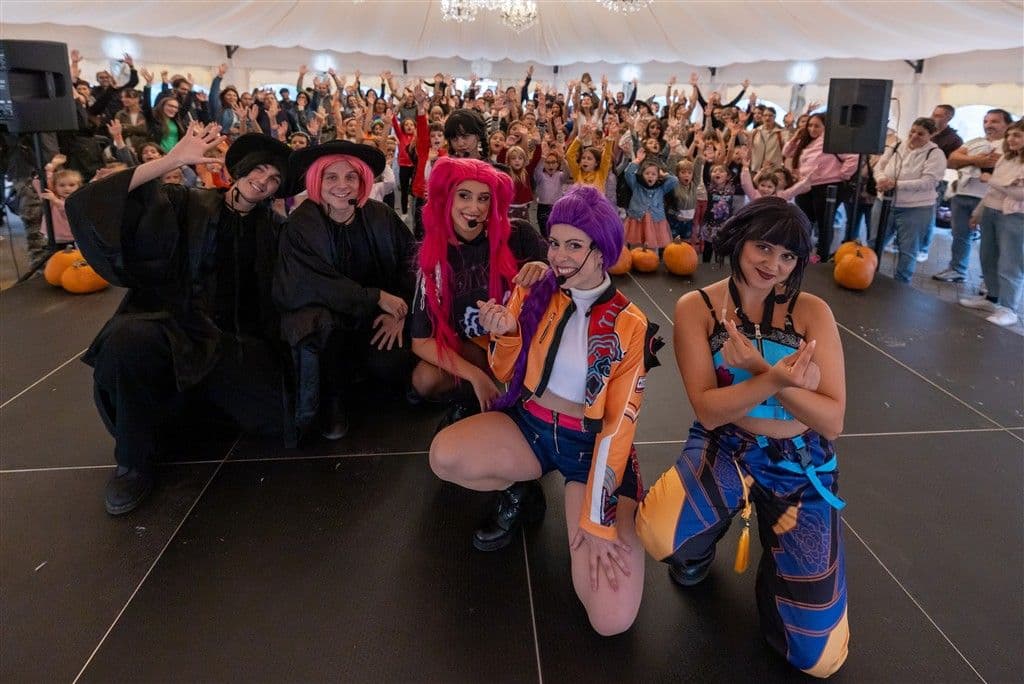 Cast e famiglie con le mani alzate nel tendone